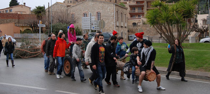 Una colla estira el carro amb el pi pel carrer, seguida per un grup de veïns.