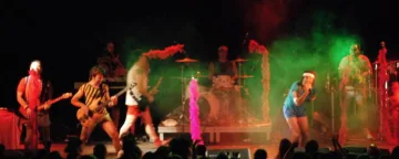 Els músics de l'orquestra actuen amb vestuari de colors entre fum verd i vermell.