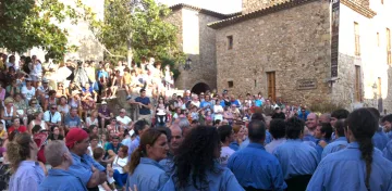 Gentada al carrer del poble durant la Festa Major, amb castellers de camisa blava en primer terme.