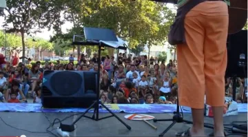 Espectacle a l'aire lliure amb el públic infantil assegut a terra davant de l'escenari.