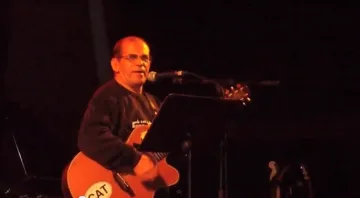 Un músic canta i toca la guitarra elèctrica en un concert nocturn.