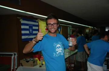 Un assistent amb la samarreta de la Festa Major 2011 alça una beguda al bar del Casino.